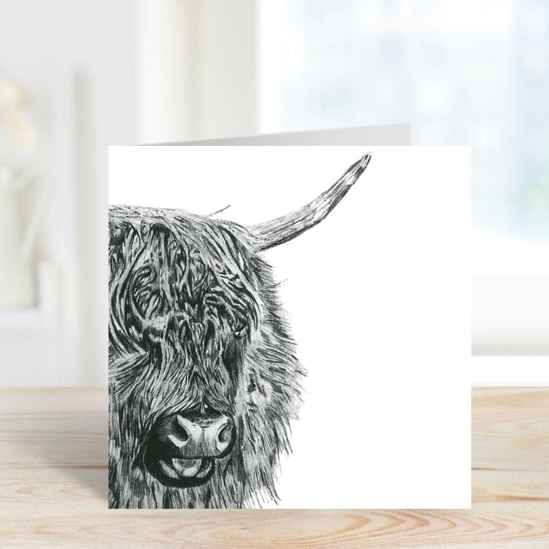 A Hand Drawn Highland Cow Greeting Card standing on a shelf, featuring a beautifully detailed illustration, designed by Libra Fine Arts.