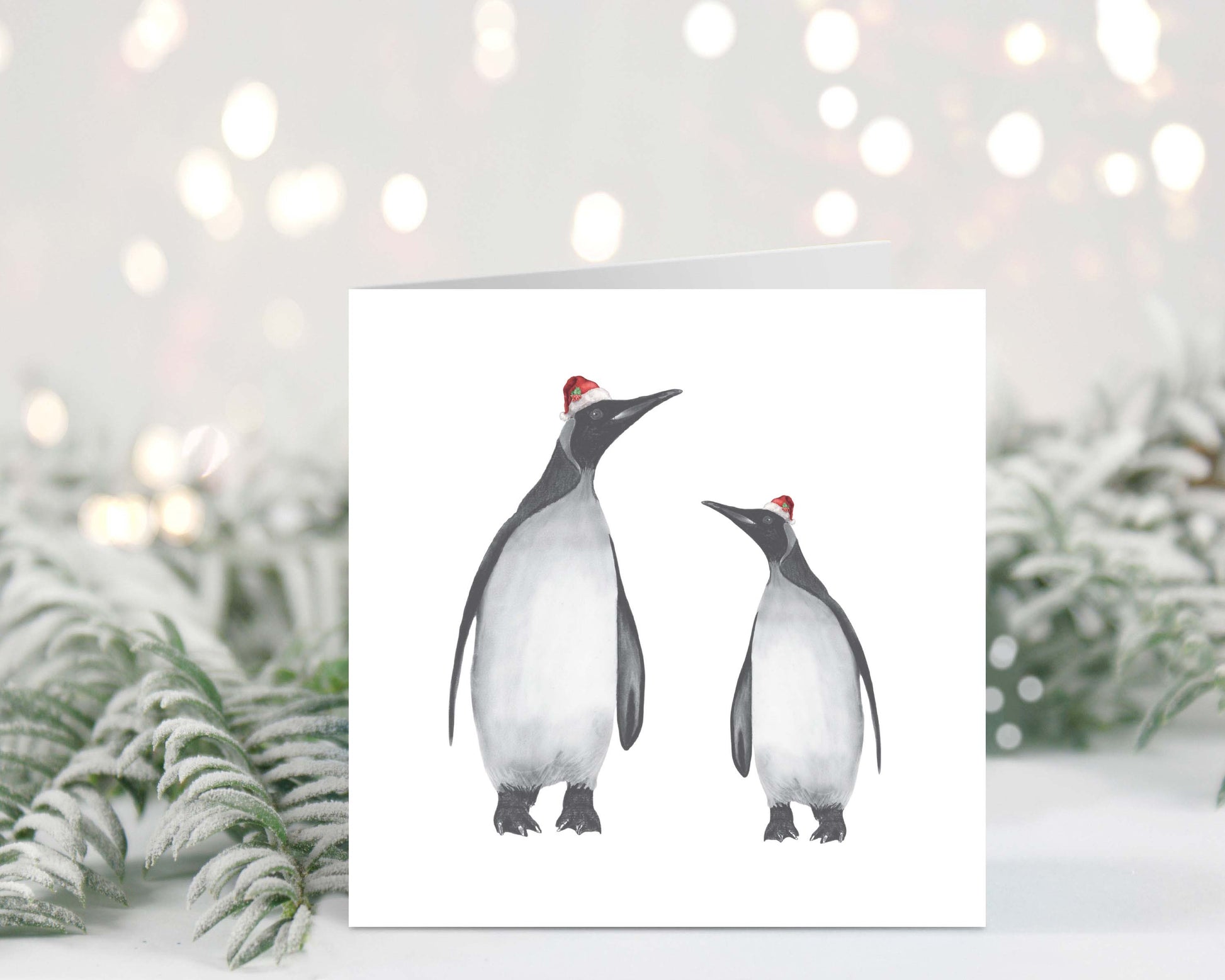 Hand-drawn Christmas card featuring Alya and baby penguin wearing festive red hats