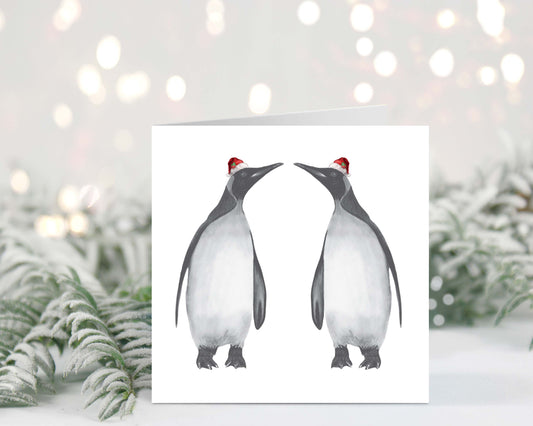 Hand-drawn festive penguin duo, Alya and friend, wearing red hats for a Christmas celebration.