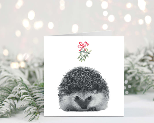 Cute hand-drawn hedgehog holding mistletoe on a festive Christmas greeting card.