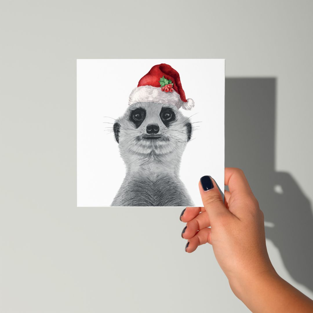 Cute hand-drawn meerkat wearing a Santa hat on a festive Christmas card