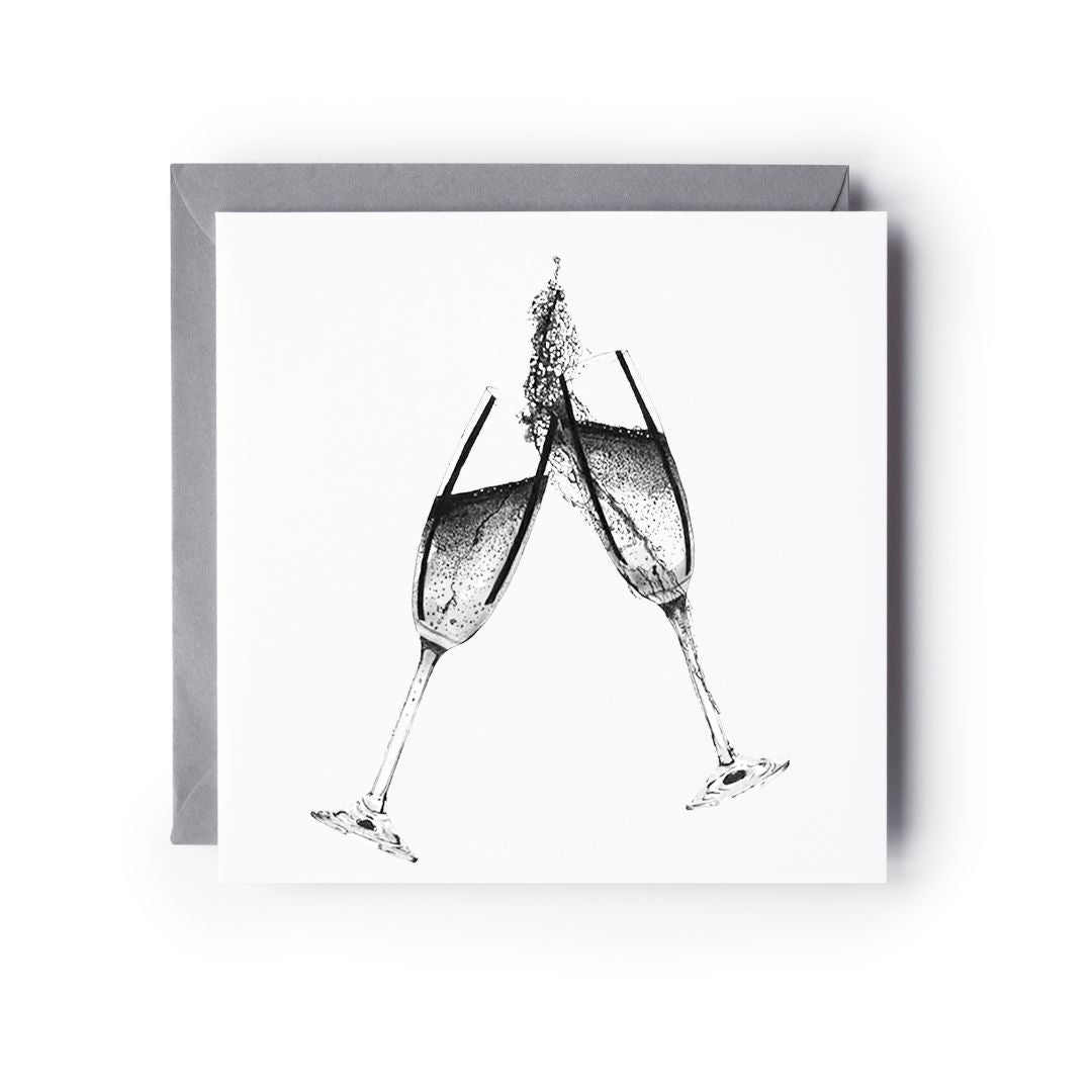 A hand-drawn "Cheers Celebration Champagne" greeting card, displayed flat with a grey envelope beside it. The card features two champagne glasses clinking in celebration, perfect for engagements, anniversaries, or birthdays. Printed on premium cardstock, it offers a high-quality, eco-conscious feel. Blank inside for a heartfelt message, making it a beautiful and thoughtful choice for marking any special occasion.