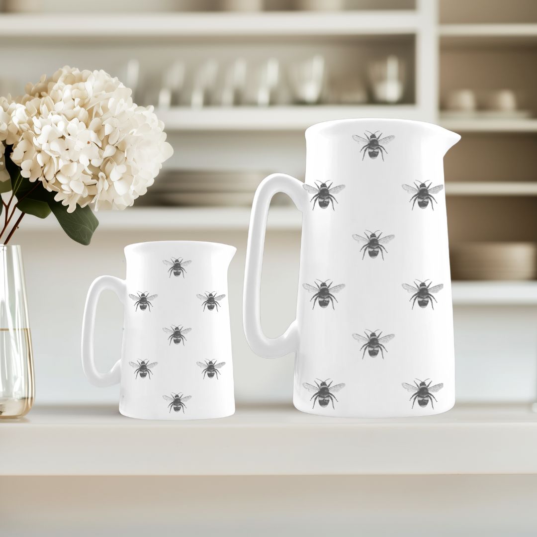 Lovely duo of fine bone china jugs featuring hand-drawn busy bees, perfect for gifting, entertaining, or brightening up your kitchen with a touch of nature.