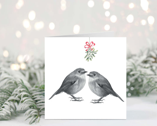 Hand-drawn festive Christmas card featuring two robins sharing a kiss under mistletoe.