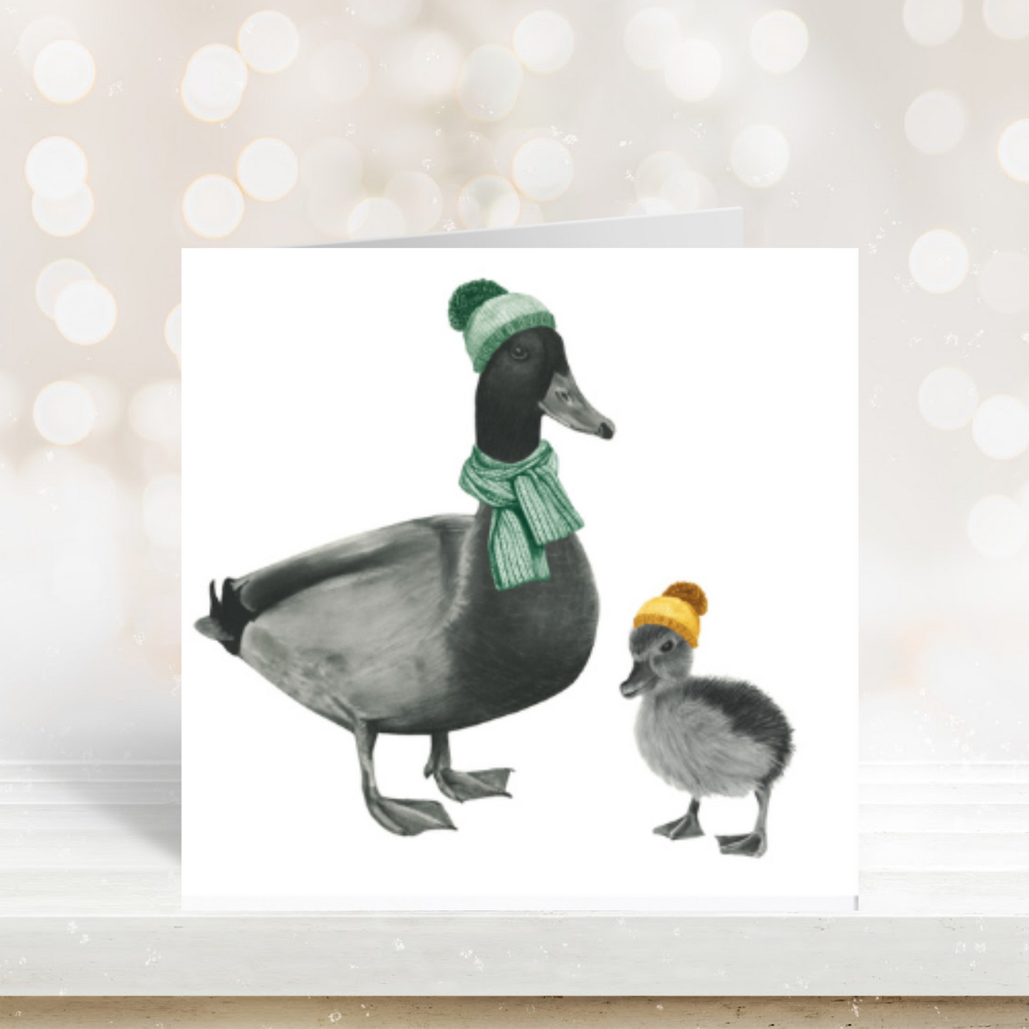 Hand-drawn winter greeting card showing a duck and duckling wrapped up warmly together.