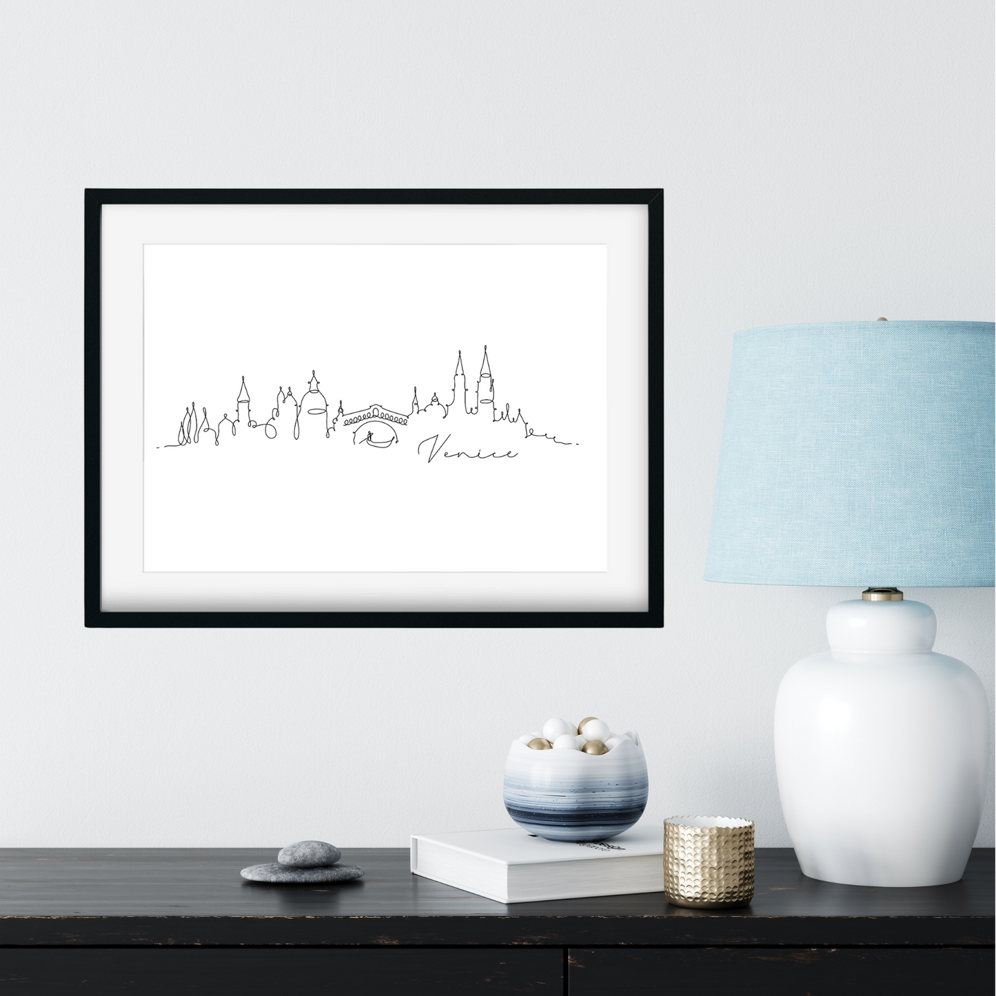 Framed city skyline print on a wall above a desk with decorative items.