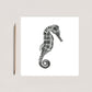 A Hand-Drawn Seahorse Greeting Card from Libra Fine Arts alongside a pencil, showcasing a detailed black and white seahorse illustration. A perfect gift for ocean lovers and art enthusiasts