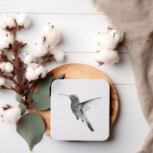 A high-quality coaster featuring a detailed hand-drawn illustration of Adhara the Hummingbird, adding a touch of nature-inspired beauty to your home. Measuring 10x10cm, this UK-made coaster is crafted from durable melamine with an eco-friendly eucalyptus core and cork backing, ensuring both style and functionality. Available individually or as a set of four, it's an ideal gift for bird enthusiasts and nature lovers.​

