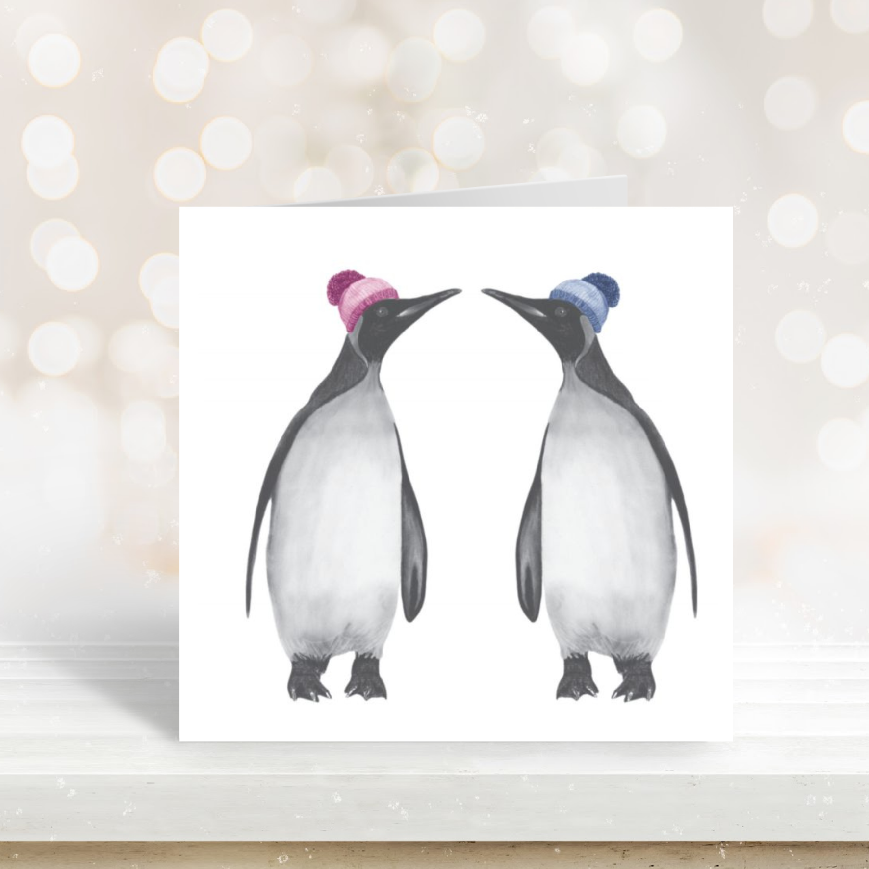 Cute illustration of two penguins bundled up in bobble hats on a seasonal card.

