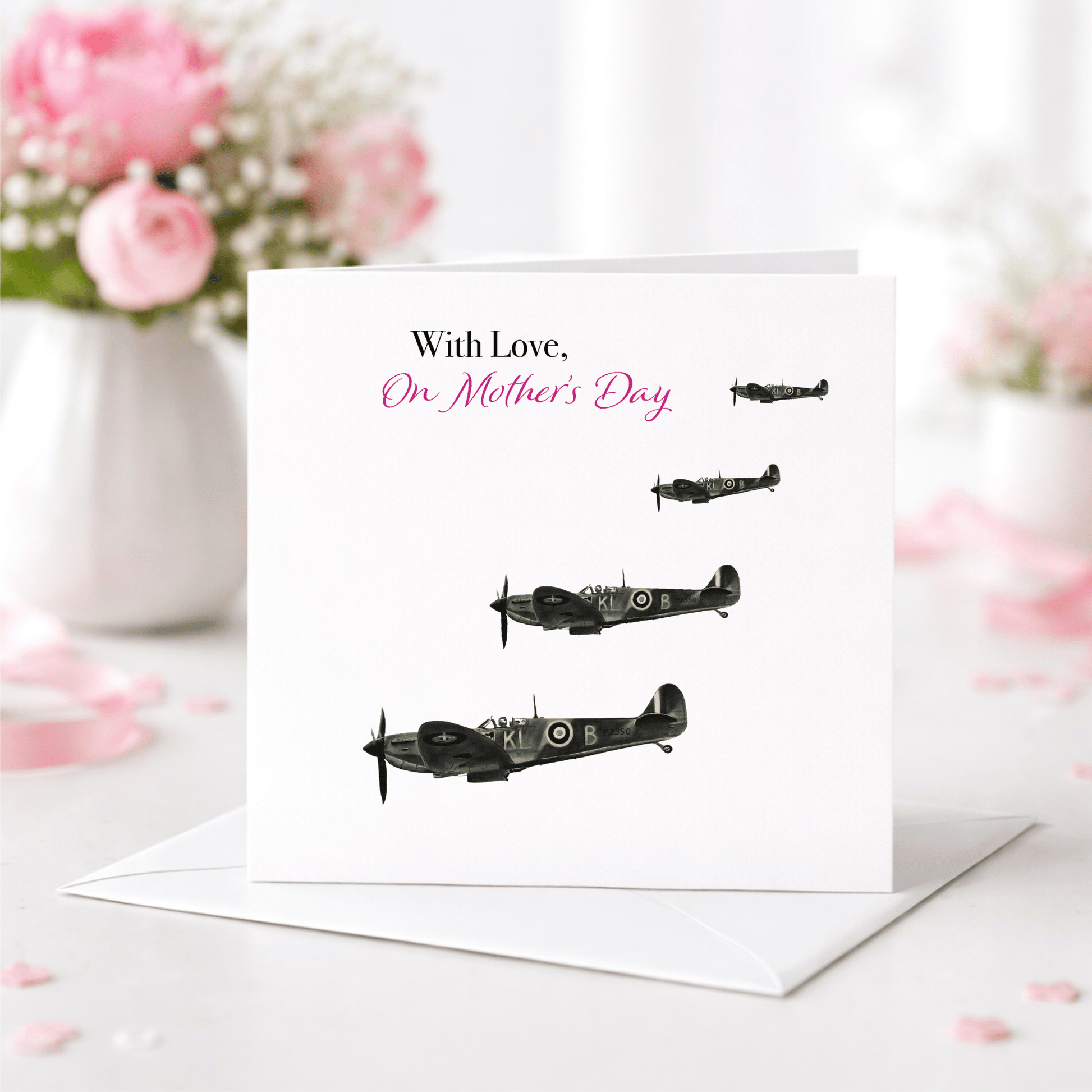 Greeting card with airplane illustrations and 'On Mother's Day' text, placed on a surface with flowers in the background.