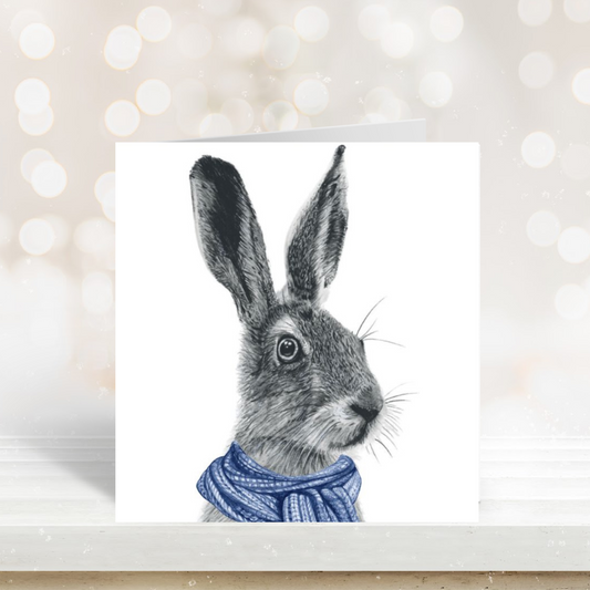 Winter hare illustration wrapped in a cozy blue scarf on a seasonal greeting card.



