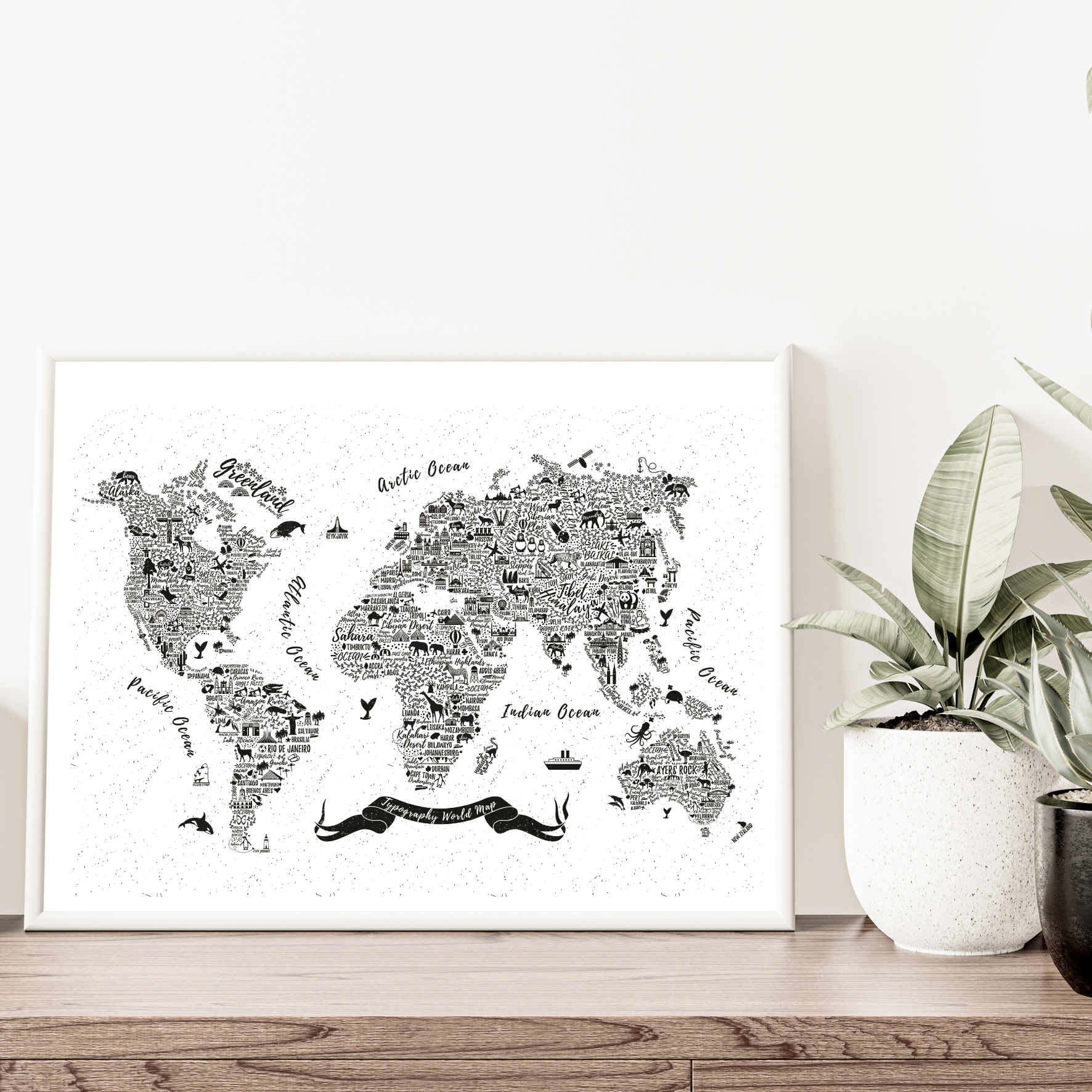 World map art print on a white wall with a plant and decorative items below.