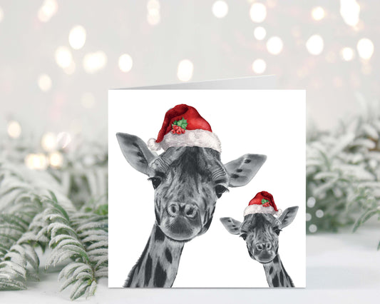 Giraffe and her baby both wearing festive red hats, captured on a charming Christmas greeting card.