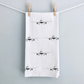 Tea towel with airplane pattern hanging on a line against a light gray background