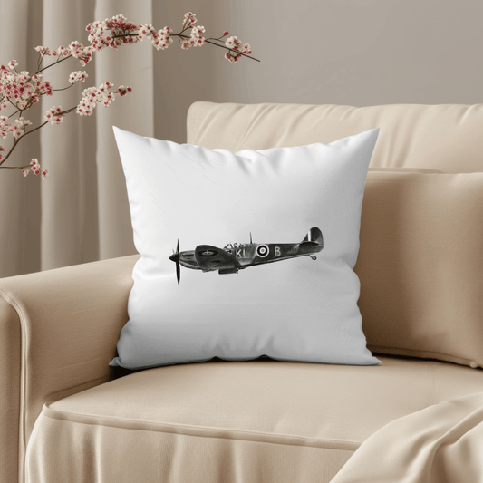 White pillow with a black airplane design on a beige couch with cherry blossoms.