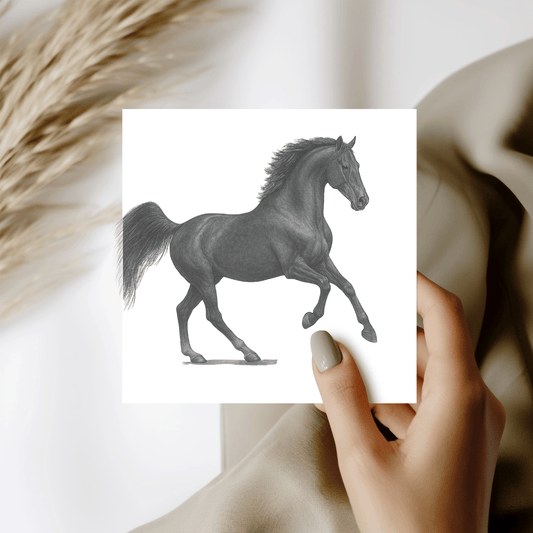 Hand holding a card with a black and white illustration of a horse against a neutral background.