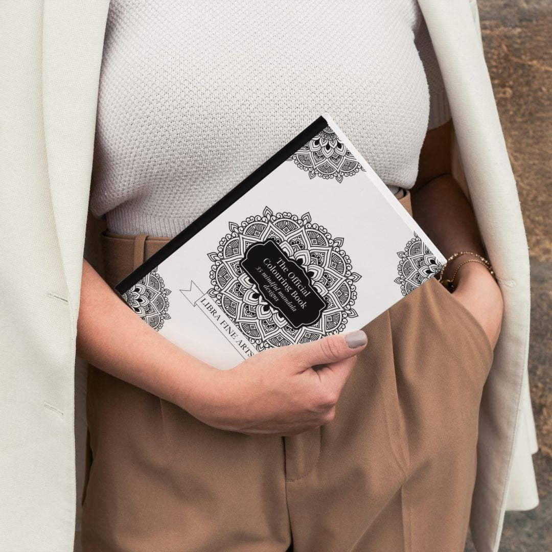 A woman holding the Mindfulness Mandala Colouring Book by Libra Fine Arts, showcasing its intricate mandala designs. The book is displayed open, highlighting the calming and detailed patterns, perfect for relaxation and creativity.








