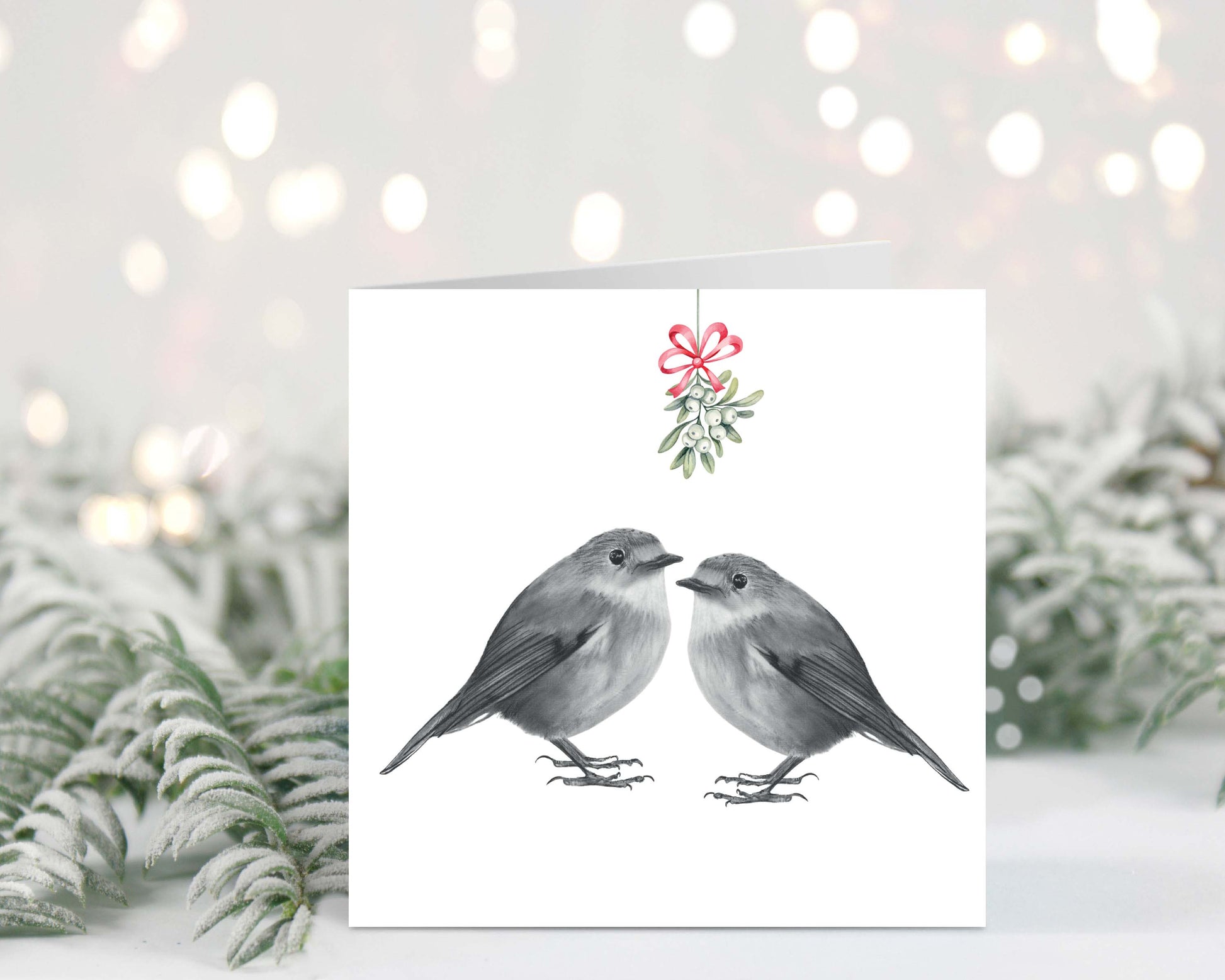 Hand-drawn festive Christmas card featuring two robins sharing a kiss under mistletoe.