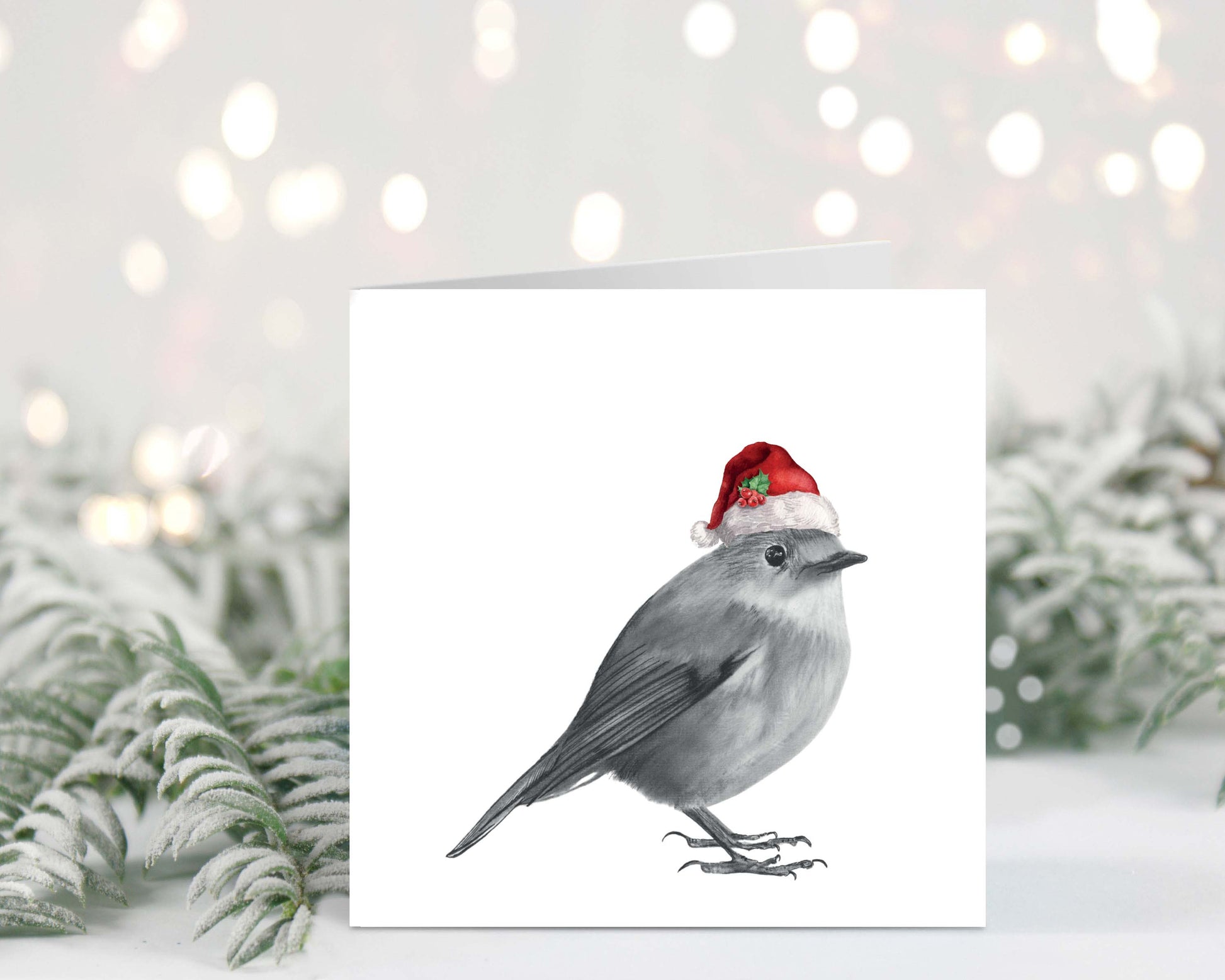Charming hand-illustrated Christmas card featuring a robin wearing a festive Santa hat, perfect for sending warm holiday wishes.