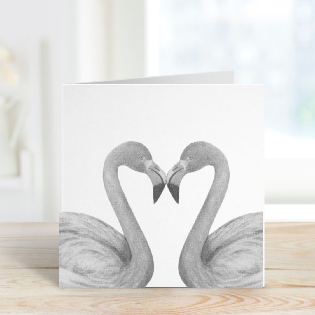 Flamingo Heart Greeting CardA graceful hand-illustrated greeting card featuring two flamingos forming a heart shape, perfect for sending love and appreciation to someone special.

