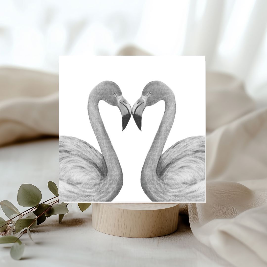 A charming hand-illustrated greeting card featuring two flamingos forming a heart shape, perfect for sending love and joy on special occasions.

