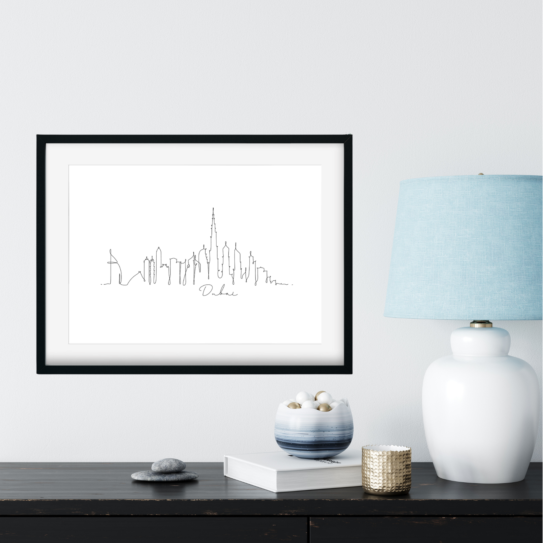 Framed black and white city skyline print on a wall above a table with decorative items.