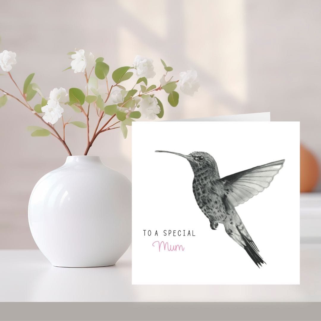 A hand-drawn "To a Special Mum" hummingbird greeting card, placed next to a vase of flowers. The card features a delicate hummingbird design, perfect for Mother’s Day or a birthday. Printed on high-quality cardstock, with a blank inside for your personal message. Ideal for mums who appreciate nature-inspired, heartfelt cards.