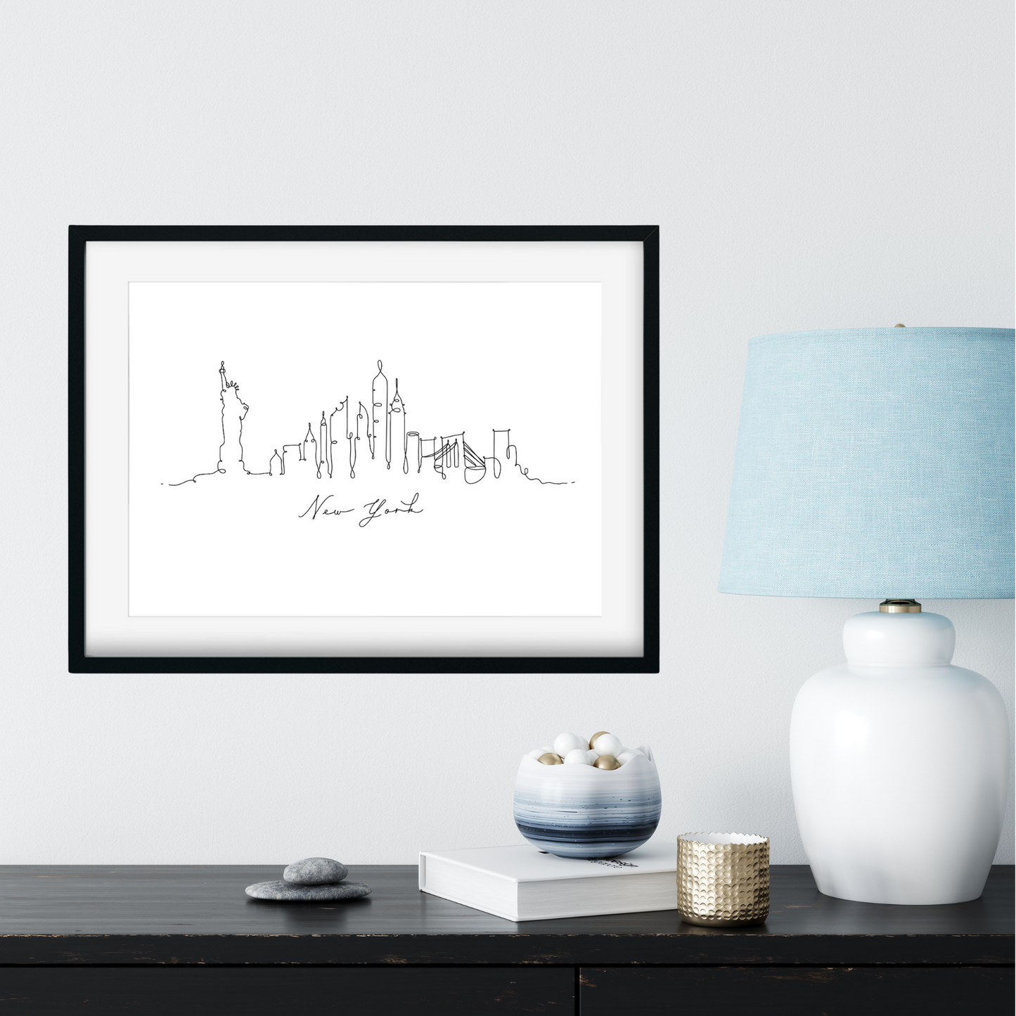 Framed artwork of a city skyline on a wall above a desk with decorative items.
