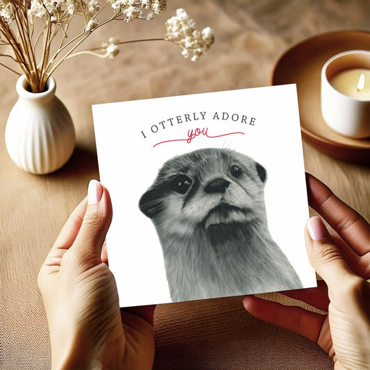 A hand-drawn 'I Otterly Adore You' greeting card with an adorable otter design, held in a woman's hands. The card comes with a vibrant red envelope, perfect for otter enthusiasts, and ideal for anniversaries, Valentine's Day, or special moments. Printed on premium cardstock with a blank interior, ready for a personalized, heartfelt message.







