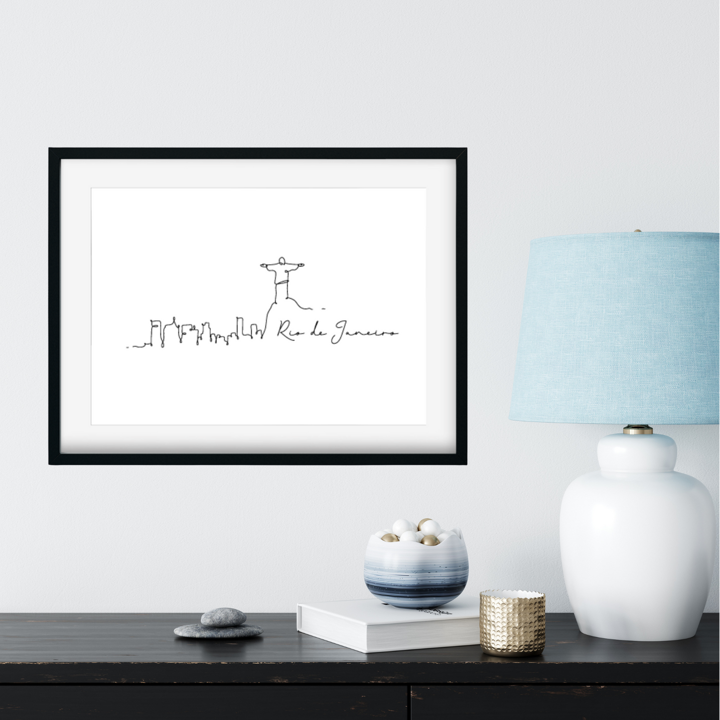 Framed artwork on a wall with a lamp and decorative items below.