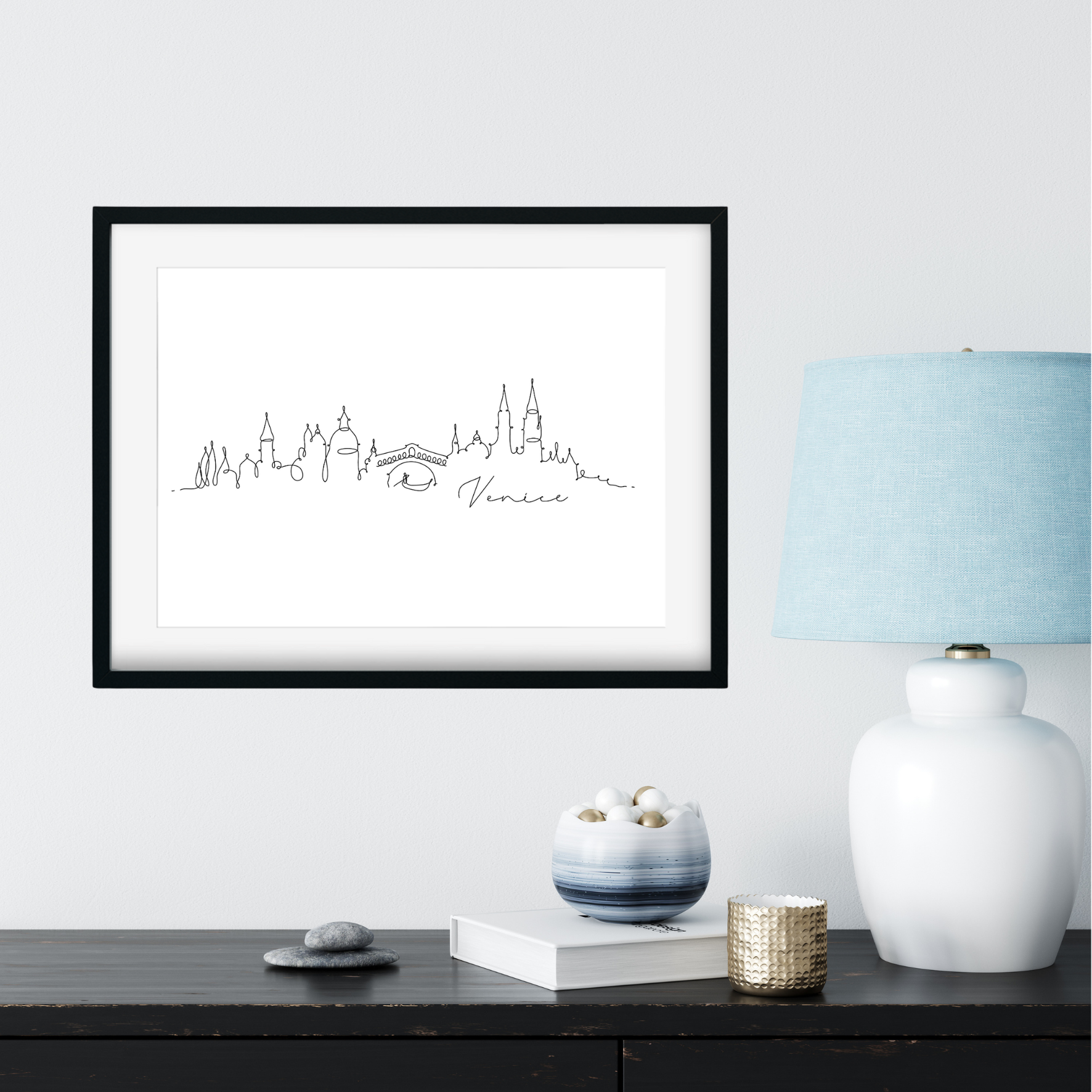 Framed city skyline print on a wall above a desk with decorative items.